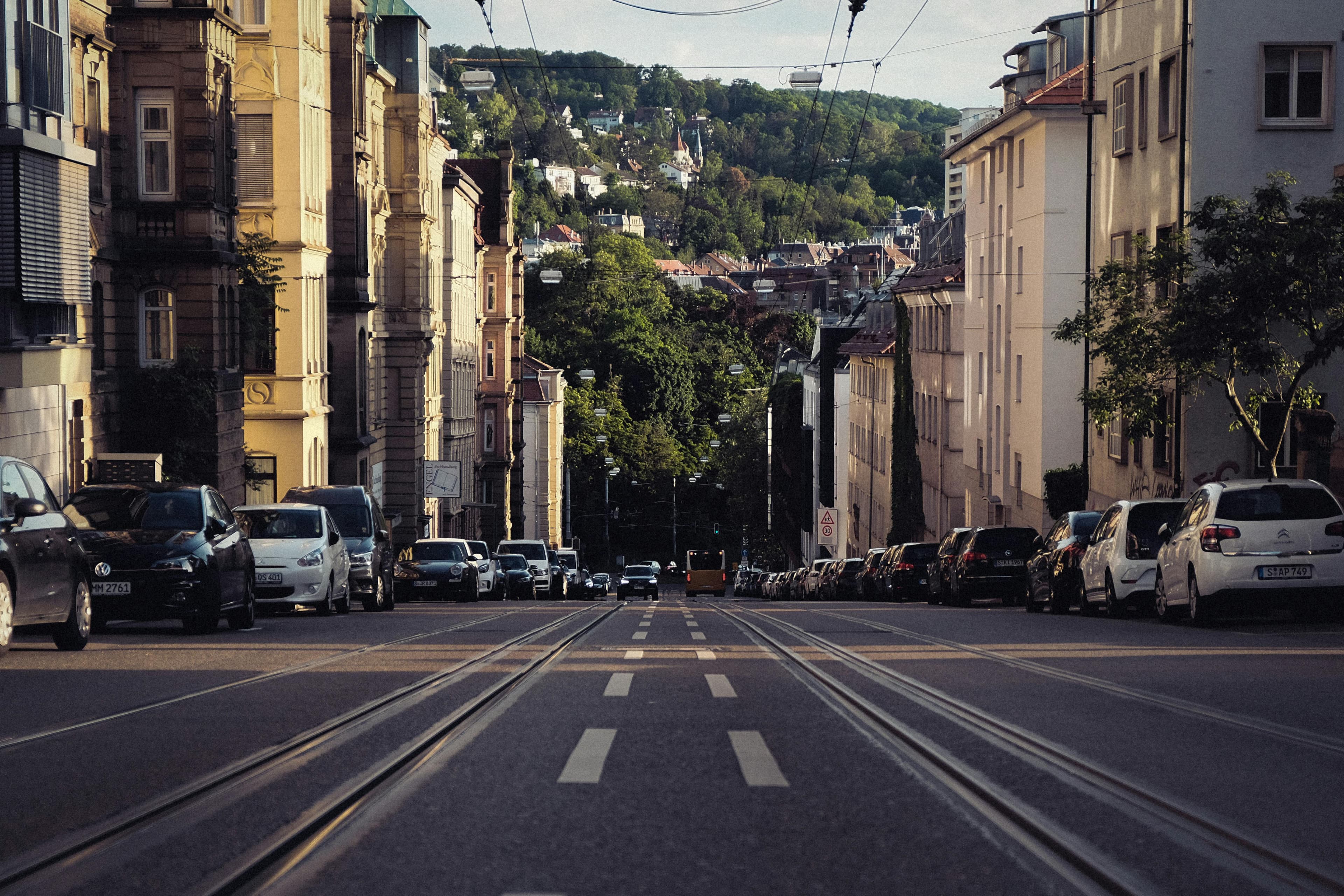 Eine Straßenansicht von Stuttgart. Es geht bergab und es verlaufen Straßenbahngleise auf der Straße.