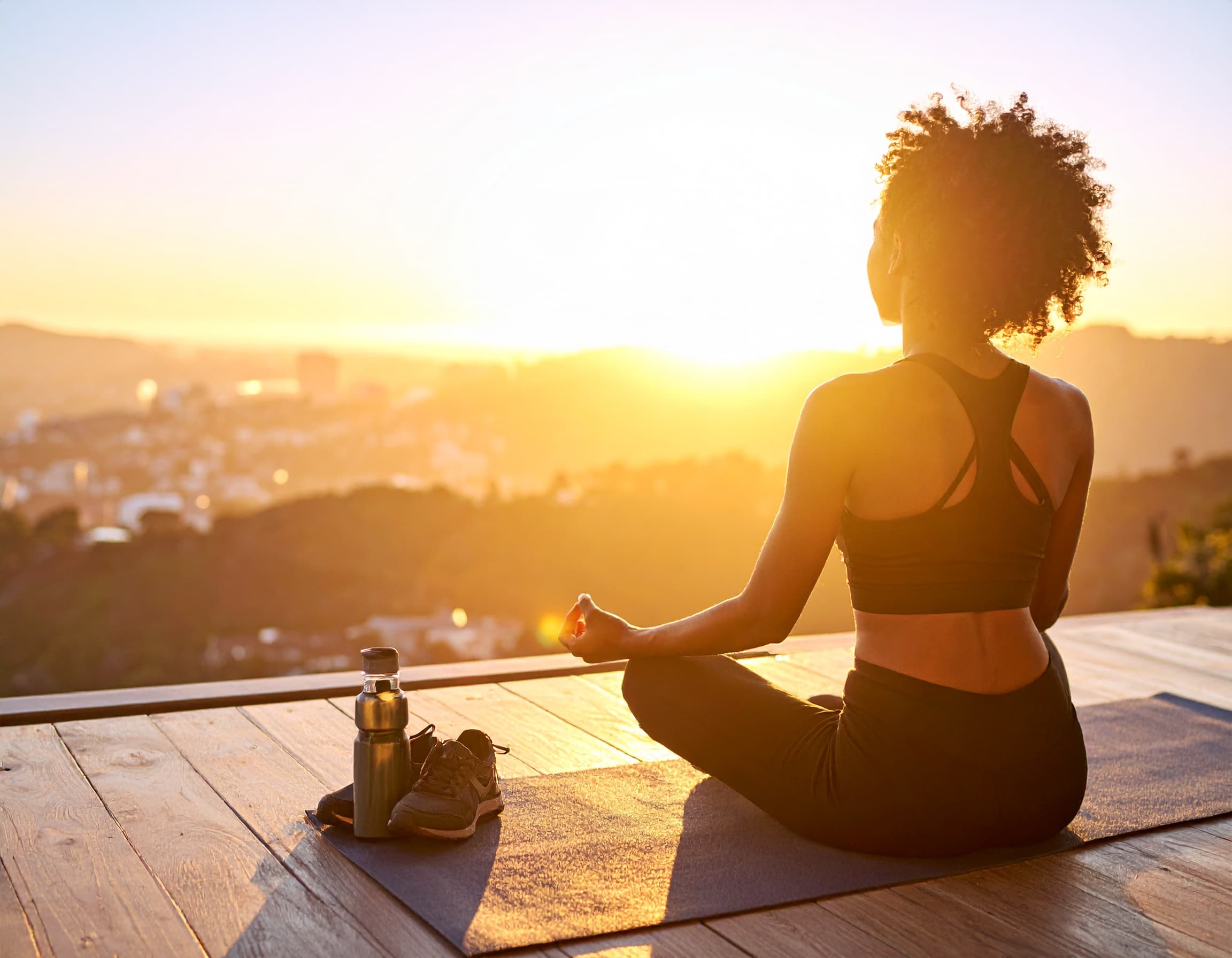 Rückansicht einer Frau in Yoga-Pose im Morgenlicht als Zeichen für Wege ADHS-Symptome zu lindern