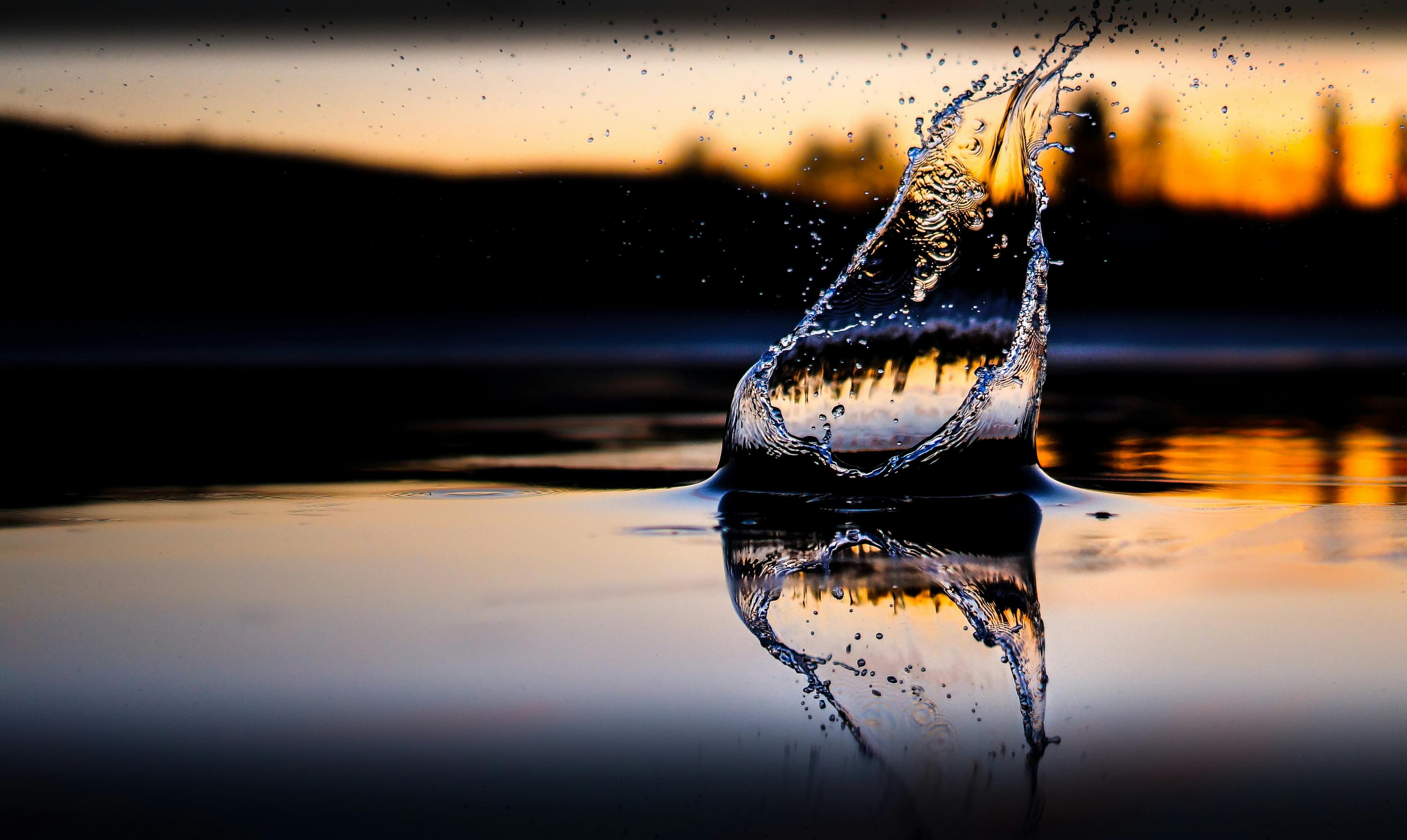 Wasser spritzt auf von der sonst glatten Oberfläche eines Sees in der Abenddämmerung