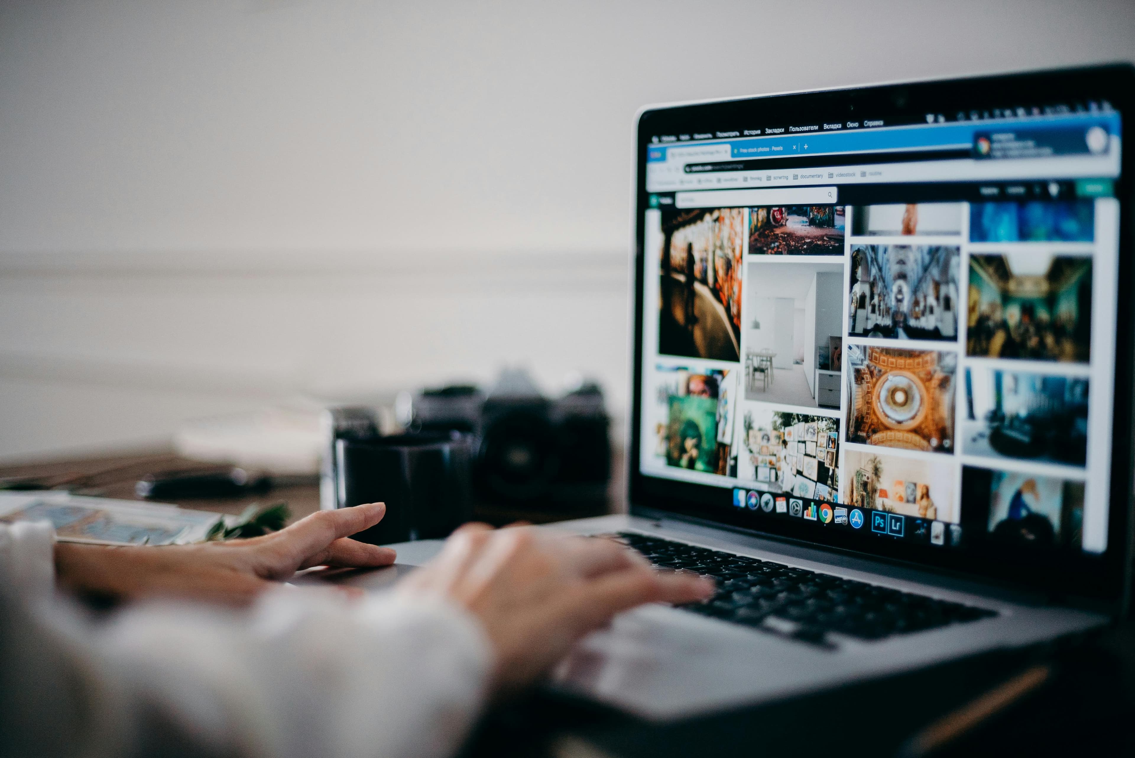 Hände tippen auf einer Laptop-Tastatur, auf dem Bildschirm eine große Galerie aus Bildkacheln – Sinnbild für hohen Medienkonsum