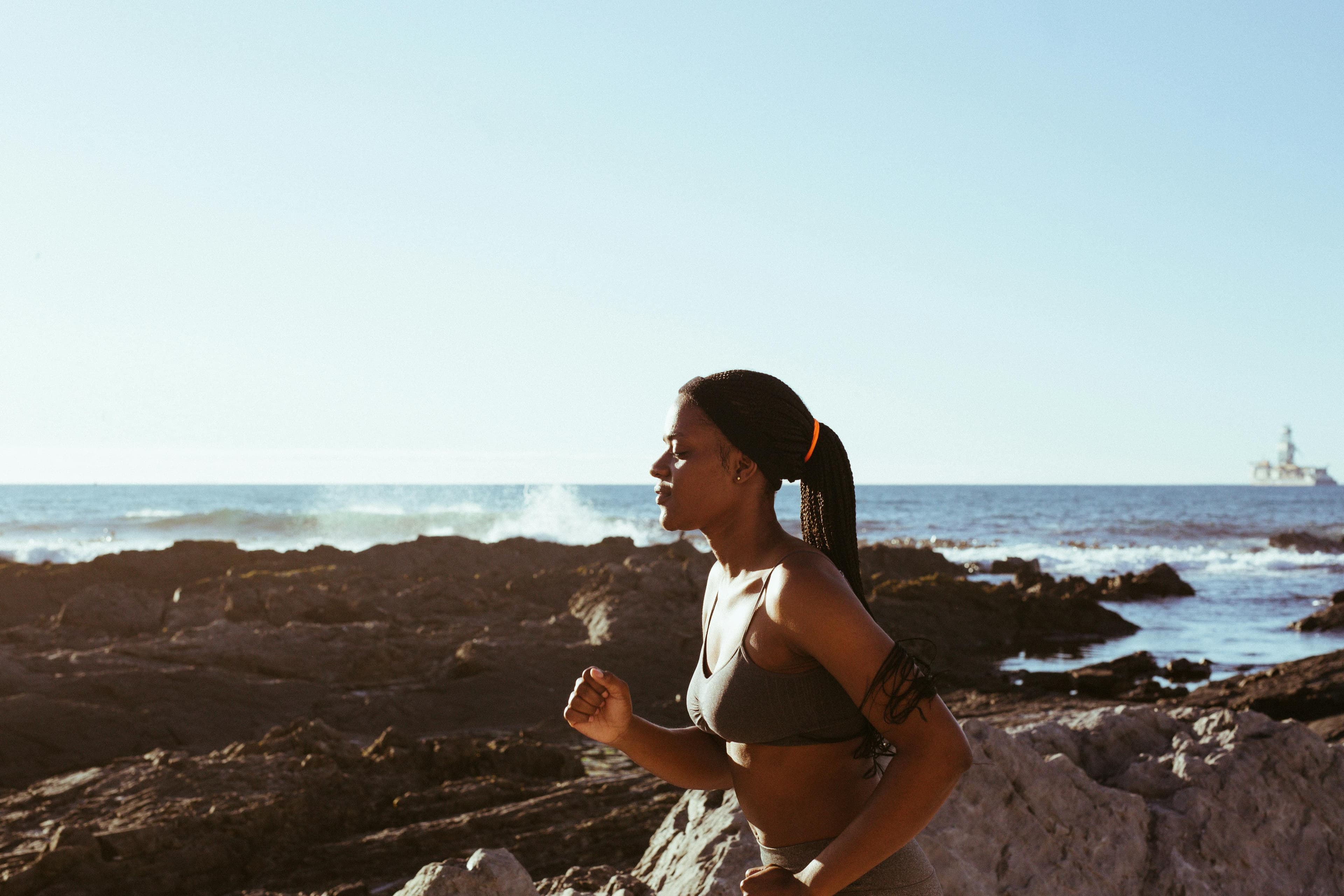 Eine Frau joggt am Meer entlang.