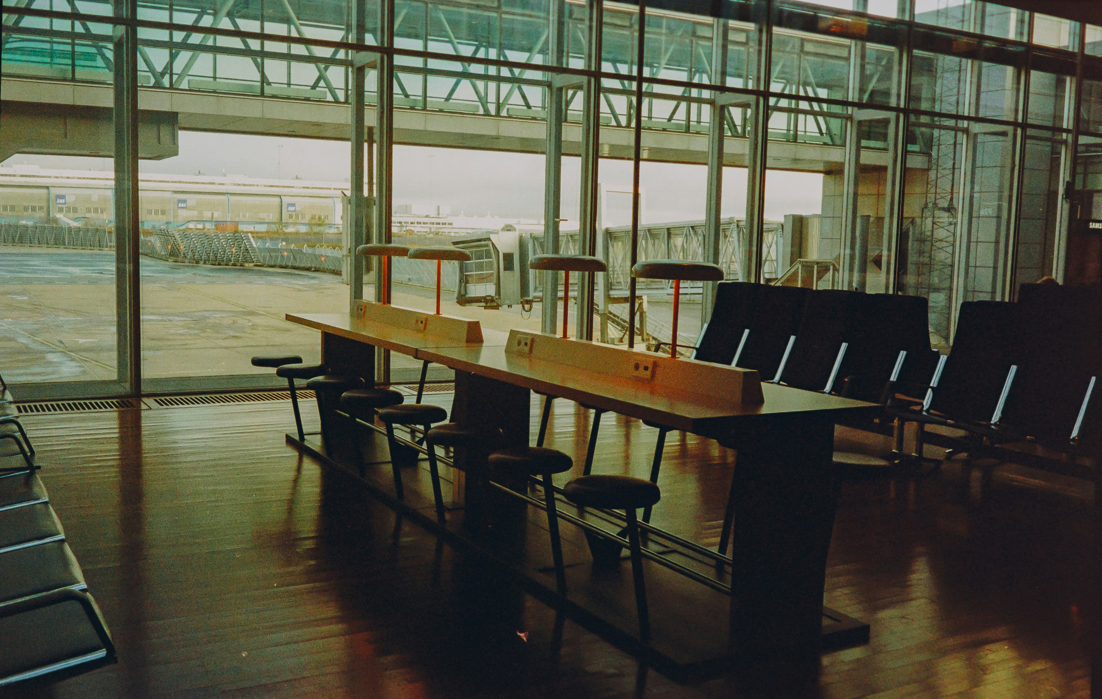 Szenerie in einem Terminal an einem Flughafen, getaucht in sepia Farben in der Abendsonne. Es sind die Stühle im Wartebereich zu sehen.